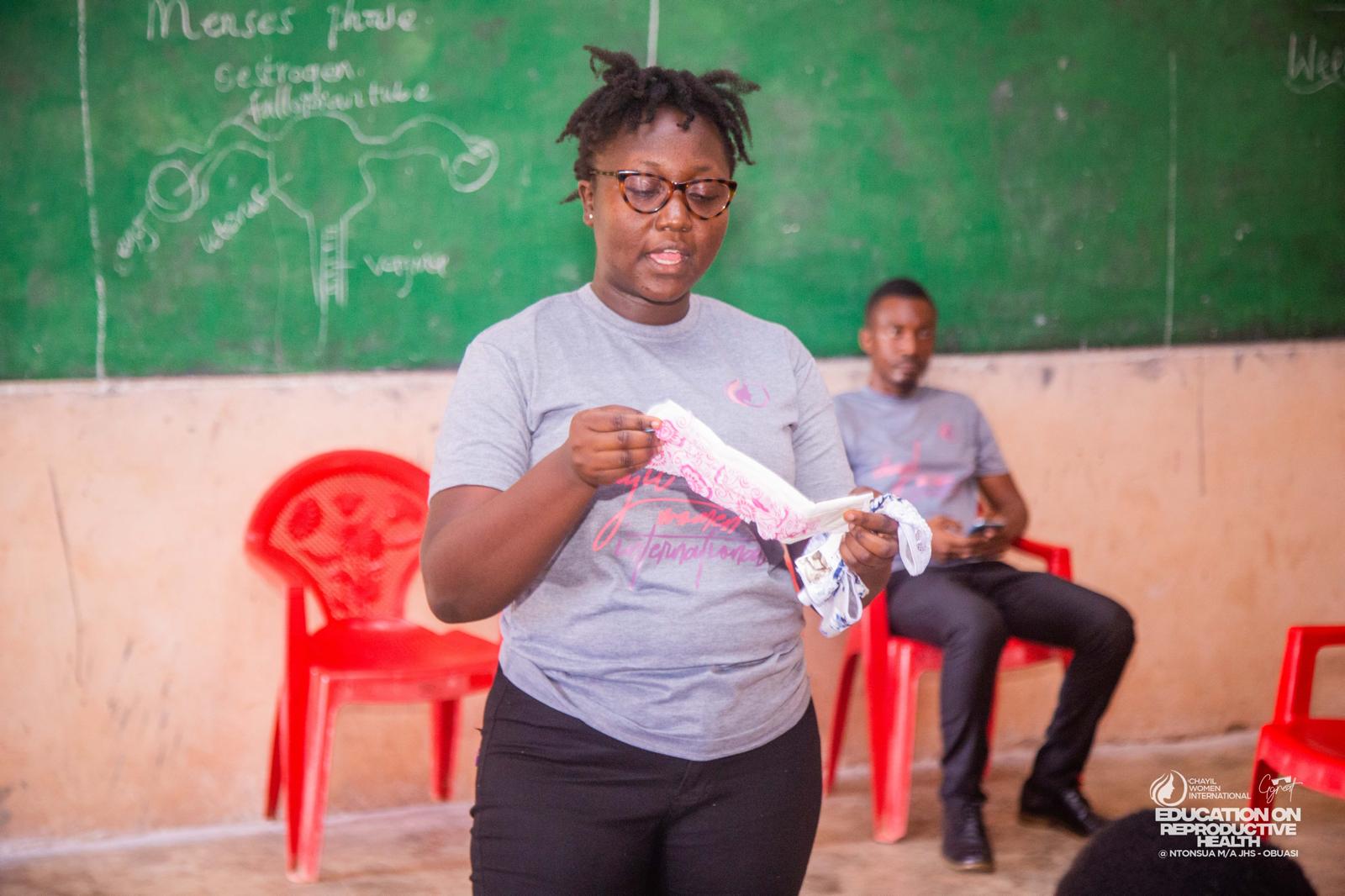 A CHAYIL volunteer leading an education session in front of a classroom blackboard